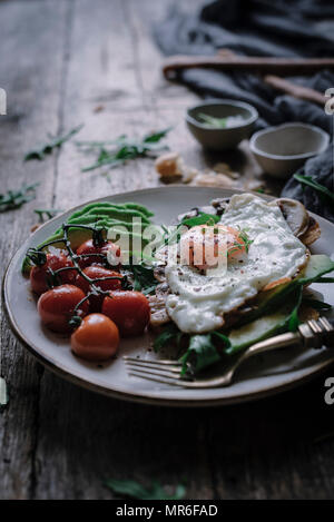 Egg and sliced avocado on toast, set on a rustic kitchen table Stock Photo
