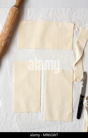 Three rectangular pieces of pastry with a rolling pin and knife. Stock Photo