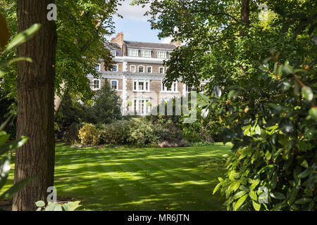A leafy garden square in Kensington, London, UK, on a summer day with terraced stucco townhouses in the background Stock Photo