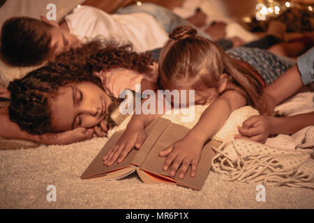 group of little children sleeping after reading book at home Stock Photo