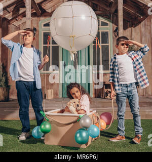 african american girl with labrador puppy sitting in air balloon box while boys looking away Stock Photo