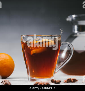 Citrus pieces splashing in cup with black spicy tea Stock Photo