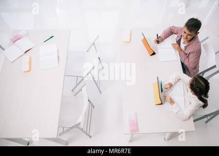 Overhead view of clasmated using digital tablets while sitting at desk in class Stock Photo