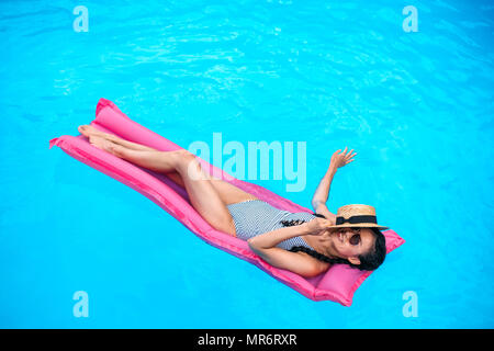 Young woman with straw hat covering face floating on air mattress in swimming  pool Stock Photo - Alamy