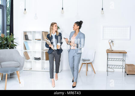 multicultural businesswomen having conversation while walking in office Stock Photo