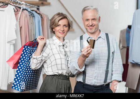 Woman standing with shopping bags and man showing a credit card Stock Photo