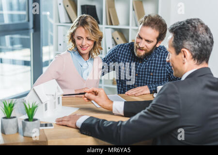 portrait of couple having meeting with realtor in real estate agency office Stock Photo