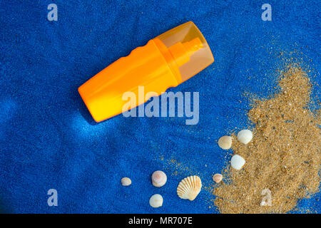 top view of sunscreen bottle on blue towel with seashells Stock Photo