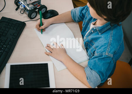 high angle view kid writing in notebook at machinery class Stock Photo