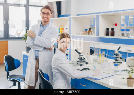 two scientists in white coats working with microscope in laboratory Stock Photo