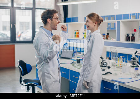 excited scientists in white coats working in laboratory Stock Photo