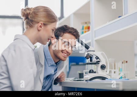 happy scientists in white coats working with microscope in laboratory Stock Photo
