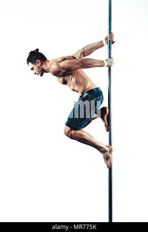 Young strong pole dancing man on white wall background Stock Photo