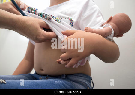 Nurse examining a little child girl by stethoscope pulling up her shirt. Periodical pediatric review concept Stock Photo