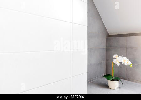 Bathroom with grey and white wall tiling and decorative orchid Stock Photo