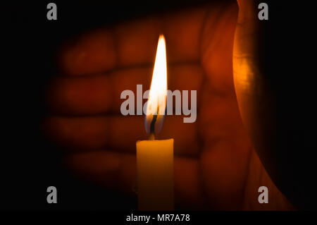 A lighted candle protected against the wind by a hand Stock Photo