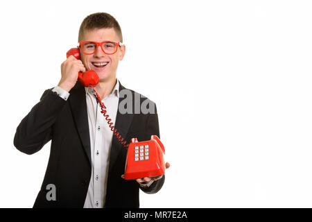 Studio shot of young happy businessman smiling and talking on ol Stock Photo