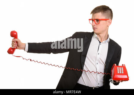 Studio shot of young businessman holding old telephone looking a Stock Photo