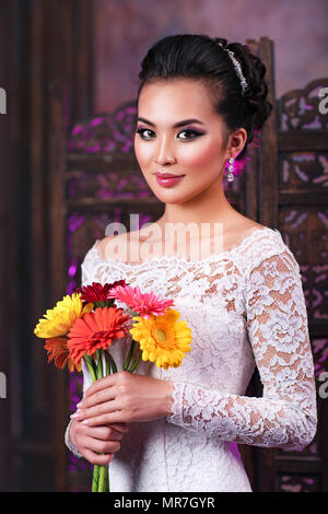 Young asian woman with flowers portrait on wall background Stock Photo