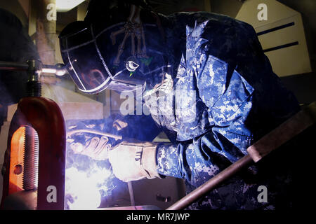 U.S. Navy Aviation Boatswain’s Mate (Equipment) 2nd Class Vincheza Carter, from Cromwell, Alabama, assigned to the air department of the Pre-Commissioning Unit Gerald R. Ford (CVN 78), welds a purchase cable connection during a socket pouring evolution in Norfolk, Va., May 19, 2017. Once complete, the sockets serve as a vital component of the ship’s flight deck arresting gear system. (U.S. Navy photo by Mass Communication Specialist 2nd Class Jason Pastrick) Stock Photo