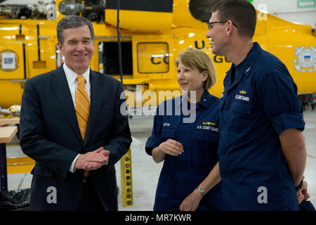 North Carolina Gov. Roy Cooper talks with Coast Guard Rear Adm. Meredith Austin, commander, 5th Coast Guard District, and Capt. Jerry Barnes, commander, Sector North Carolina, during a visit to Base Elizabeth City, May 22, 2017. The governor's visited included tours of the air station, the boat station and the Aviation and Technical Training Center on base. (U.S. Coast Guard phot by Petty Officer 2nd Class Nate Littlejohn/Released) Stock Photo