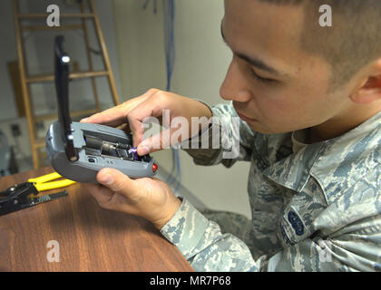Senior Airman assigned to the 88th Communications Squadron is a cable systems maintenance technician in the United States Air Force responsible for installing and maintaining fiber optic and telephone infrastructure at Wright-Patterson Air Force Base. The archival image documents the attachment of terminal ends to fiber optic cable for connection to computer servers on May 10, 2017. Stock Photo