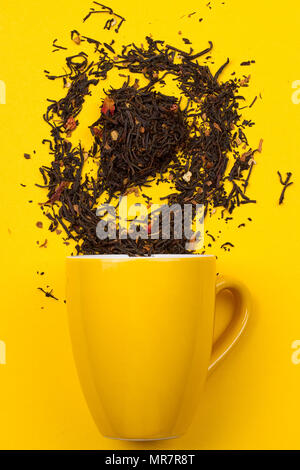 Falling driedn teain cup on yellow background white background Stock Photo