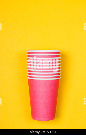 Stacks of pink paper cups on yellow background Stock Photo