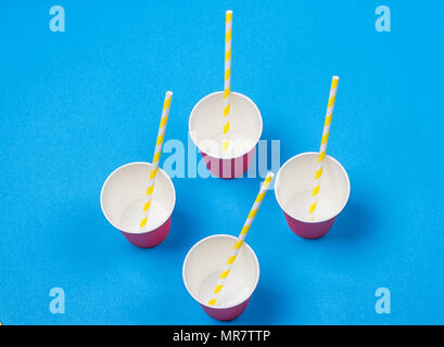 a bundle of multi-colored drinking straws in a paper Cup on a blue background. fashion minimal. flat lay Stock Photo