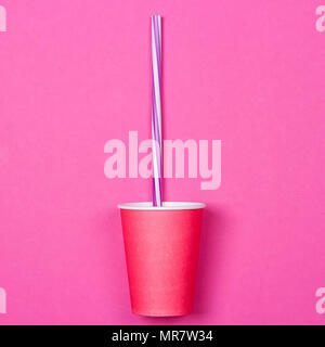 a bundle of multi-colored drinking straws in a paper Cup on a pink background. fashion minimal. flat lay Stock Photo