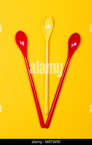 Set of multi-colored long spoons on a yellow background Stock Photo