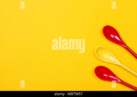 Set of multi-colored long spoons on a yellow background Stock Photo