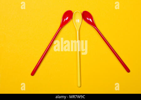 Set of multi-colored long spoons on a yellow background Stock Photo