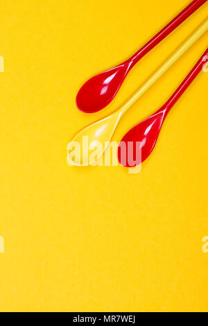 Set of multi-colored long spoons on a yellow background Stock Photo