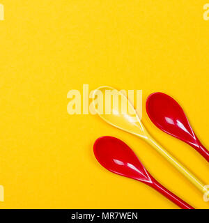 Set of multi-colored long spoons on a yellow background Stock Photo