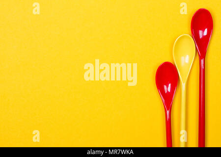 Set of multi-colored long spoons on a yellow background Stock Photo