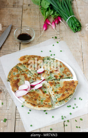 Homemade appetizing scallion pancakes with a bunch of green onions and radishes. Rustic style. Stock Photo