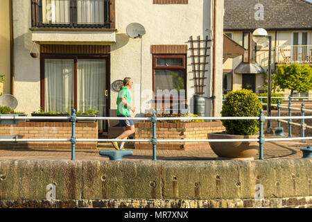 Person jogging on the harbour wall around new homes in the Penarth Marina Stock Photo