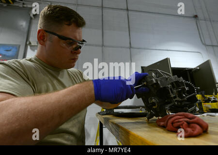 Airman 1st Class is an enlisted rank in the United States Air Force. The archival image records a 20th Equipment Maintenance Squadron weapons technician at Shaw Air Force Base, South Carolina, on May 22, 2017 using a hammer and punch to secure roll pins on an M61A1 Vulcan 20 mm rotary cannon exit unit. The historical photographic print documents sprocket and gear shaft maintenance for ammunition feed. Stock Photo