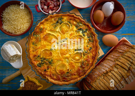 Quiche recipe with spinach and goats cheese on blue table Stock Photo