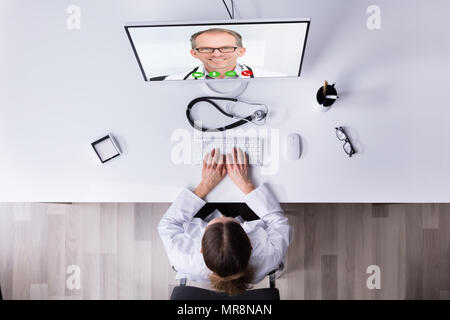 Elevated View Of A Female Doctor Video Conferencing With Male Colleague On Computer Stock Photo