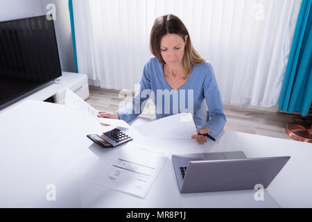 Elevated View Of Woman Calculating Invoice With Calculator At Home Stock Photo