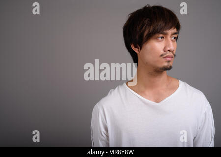 Young Asian man against gray background