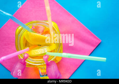Ice cold Lemonade in glass jar with straws and icy plastic flamingos isolated on blue backdrop Stock Photo
