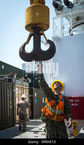 A Boatswain’s Mate guides a crane to offload containers from USNS ...