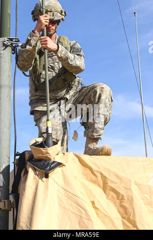 Spc. Thomas Hartzog, an air defense battle management system operator of Battery C, 1st Battalion, 204th Air Defense Artillery Regiment, sets up an antenna on top of a tactical vehicle as the battalion sets up its operations center May 29, 2017 at the National Training Center, Fort Irwin, California. (Mississippi National Guard photo by Spc. Justin Humphreys, 102d Public Affairs Detachment) Stock Photo