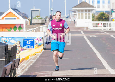 A male jogger wearing an aston villa shirt running along the hastings seafront participating in park run, hastings, east sussex, uk Stock Photo