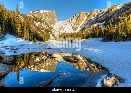 Morning Sun on Hallett Peak is reflected in half frozen Dream Lake in Rocky Mountain National Park, Colorado Stock Photo