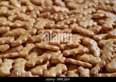 A huge bunch of salted biscuits of small sizes as a closed pattern or texture. A large amount of salted cracker in golden yellow tones Stock Photo