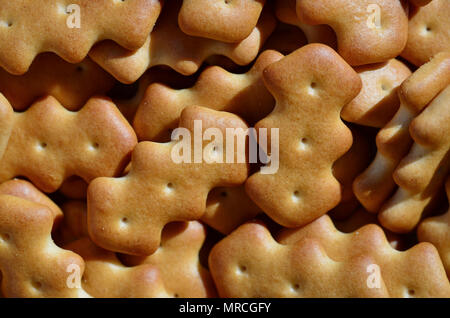 A huge bunch of salted biscuits of small sizes close-up. Macro shot of a large amount of salt cracker in golden yellow tones Stock Photo